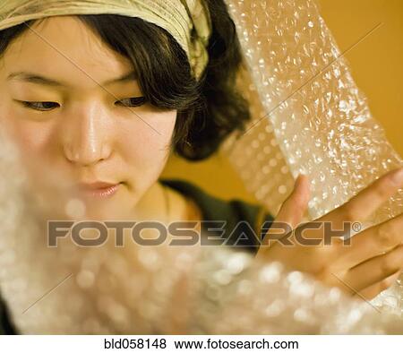 Asian woman pushing aside bubble wrap View Large Photo Image Stock Photo - Asian woman pushing aside bubble wrap. Fotosearch