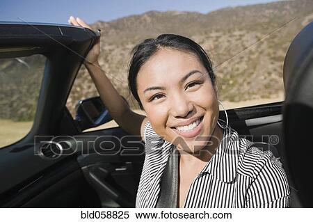 Stock Photography - Asian woman sitting in convertible car. Fotosearch