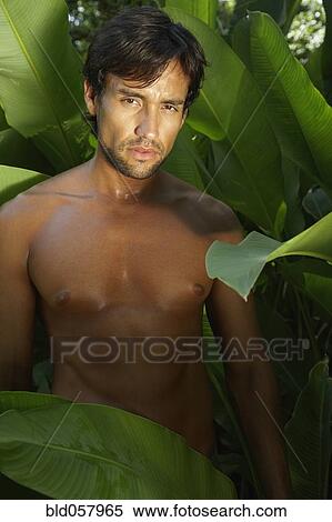 Stock Photography - Bare-chested Hispanic man next to plants. Fotosearch
