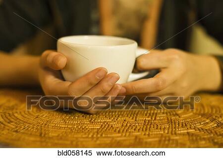 Stock Photography - Close up of woman’s hands holding tea mug. Fotosearch