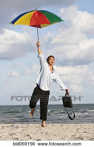 Hispanic businessman holding beach umbrella View Large Photo Image Stock Photograph - Hispanic businessman holding beach umbrella. Fotosearch