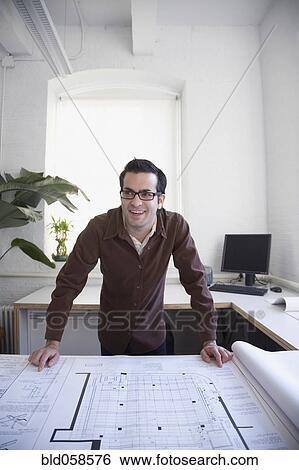 Hispanic businessman leaning on blueprints View Large Photo Image Stock Photograph - Hispanic businessman leaning on blueprints. Fotosearch