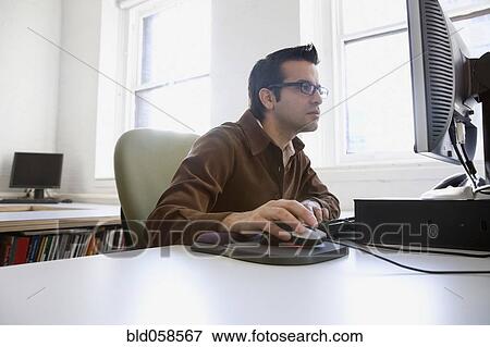Stock Photo - Hispanic businessman looking at computer. Fotosearch