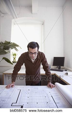 Stock Photography - Hispanic businessman looking at blueprints. Fotosearch