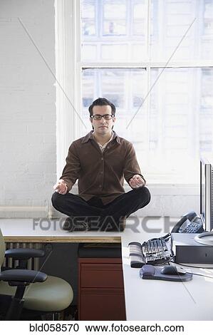 Stock Image - Hispanic businessman meditating. Fotosearch