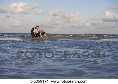 Stock Image - Hispanic businessman on sandbar. Fotosearch