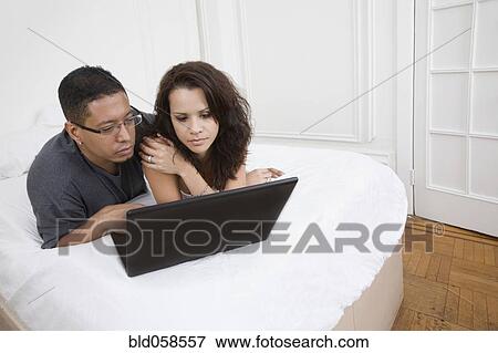 Stock Photo - Hispanic couple looking at laptop. Fotosearch