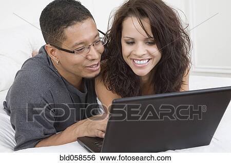 Stock Photograph - Hispanic couple looking at laptop. Fotosearch