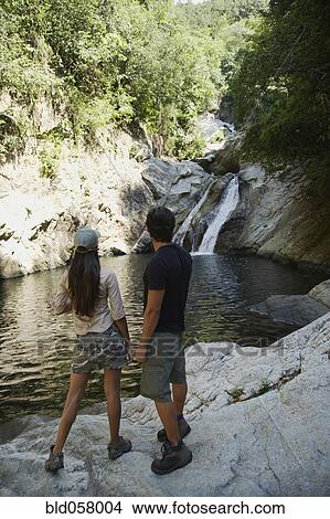 Picture - Hispanic couple looking at waterfall. Fotosearch