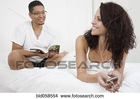 Picture - Hispanic couple relaxing on bed. Fotosearch