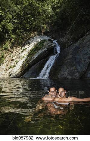 Stock Image - Hispanic couple swimming in water. Fotosearch