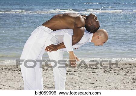 Stock Photograph - Hispanic man balancing African man on back. Fotosearch