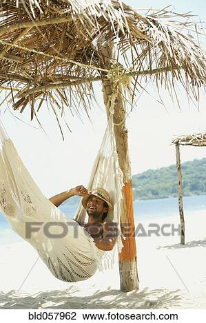 Stock Image - Hispanic man laying in hammock. Fotosearch