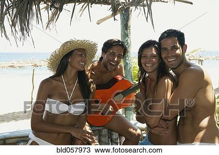 Stock Image - Hispanic man playing guitar for friends. Fotosearch