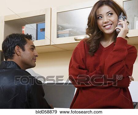 Hispanic man watching girlfriend talk on telephone View Large Photo Image Stock Photo - Hispanic man watching girlfriend talk on telephone. Fotosearch