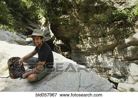 Hispanic man with back pack sitting on rocks View Large Photo Image Stock Photo - Hispanic man with back pack sitting on rocks. Fotosearch
