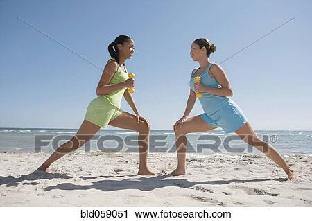 Stock Image - Hispanic woman exercising on beach. Fotosearch