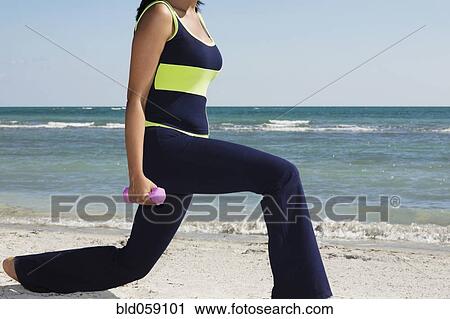 Stock Image - Hispanic woman exercising with dumbbells. Fotosearch
