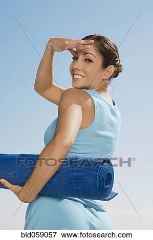 Stock Photo - Hispanic woman holding yoga mat. Fotosearch