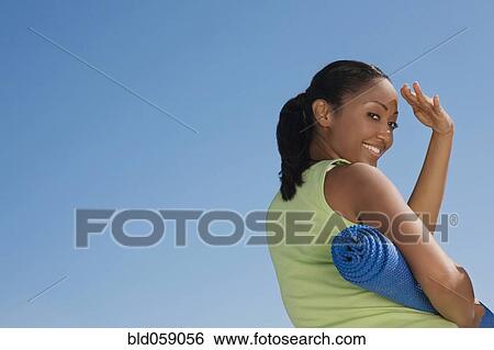 Stock Photograph - Hispanic woman holding yoga mat. Fotosearch