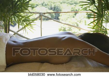 Stock Image - Hispanic woman laying on spa table. Fotosearch