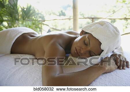 Stock Image - Hispanic woman laying on spa table. Fotosearch