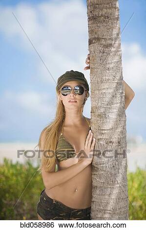 Hispanic woman leaning on palm tree View Large Photo Image Stock Photograph - Hispanic woman leaning on palm tree. Fotosearch