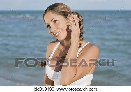 Hispanic woman listening to seashell View Large Photo Image Stock Image - Hispanic woman listening to seashell. Fotosearch