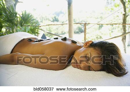 Stock Photo - Hispanic woman receiving spa stone treatment. Fotosearch