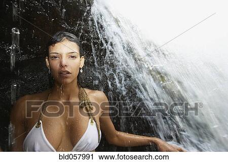 Stock Image - Hispanic woman under waterfall. Fotosearch
