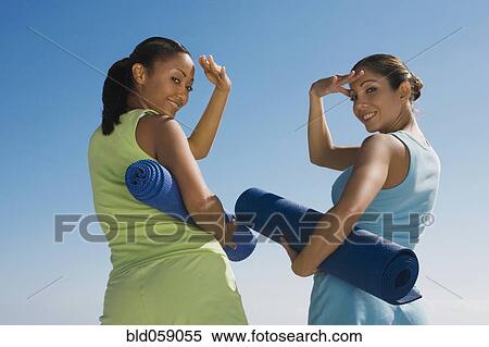 Stock Photography - Hispanic women holding yoga mats. Fotosearch