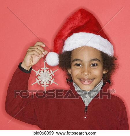 Stock Photo - Mixed Race boy holding Christmas ornament. Fotosearch