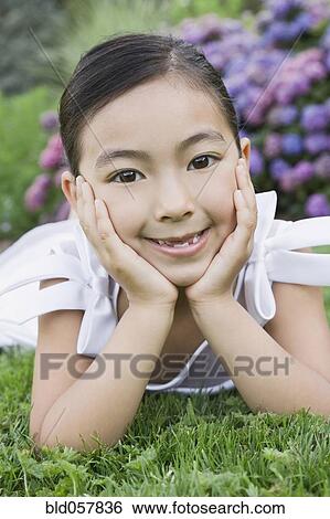 Stock Photograph - Mixed Race girl laying in grass. Fotosearch