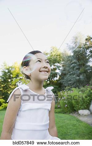 Stock Photo - Mixed Race girl playing with bubbles. Fotosearch