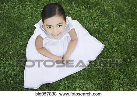 Mixed Race girl sitting in grass View Large Photo Image Stock Photo - Mixed Race girl sitting in grass. Fotosearch