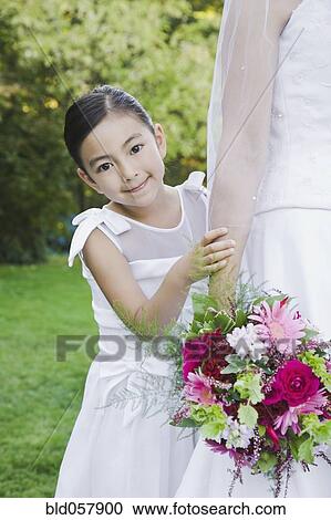 Stock Image - Mixed Race girl standing behind bride. Fotosearch