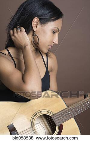 Mixed Race woman holding guitar View Large Photo Image Stock Photo - Mixed Race woman holding guitar. Fotosearch