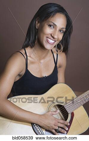 Stock Photo - Mixed Race woman holding guitar. Fotosearch