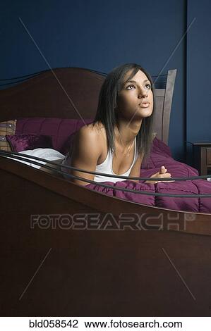 Stock Image - Mixed Race woman laying on bed. Fotosearch