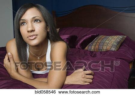 Mixed Race woman laying on bed View Large Photo Image Stock Photograph - Mixed Race woman laying on bed. Fotosearch