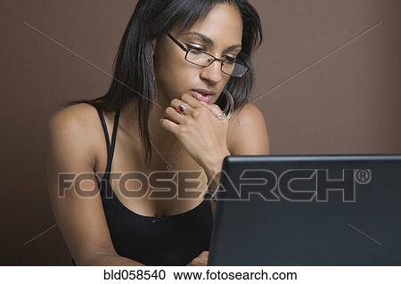 Stock Image - Mixed Race woman looking at laptop. Fotosearch
