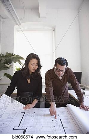 Picture - Multi-ethnic businesspeople looking at blueprints. Fotosearch
