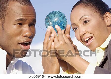 Multi-ethnic businesspeople looking at glass orb View Large Photo Image Picture - Multi-ethnic businesspeople looking at glass orb. Fotosearch