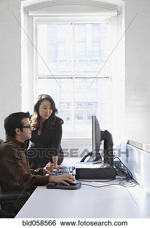 Stock Photograph - Multi-ethnic businesspeople looking at computer. Fotosearch