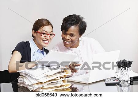 Stock Photo - Multi-ethnic businesswomen looking at paperwork. Fotosearch