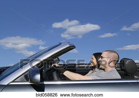 Stock Photograph - Multi-ethnic couple driving in convertible car. Fotosearch
