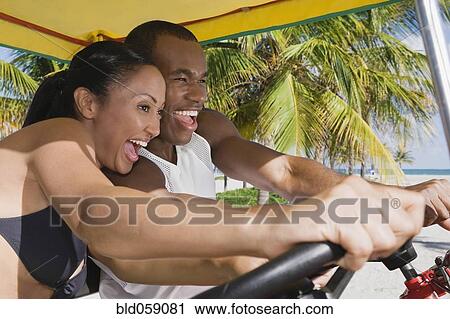 Multi-ethnic couple driving pedal cart View Large Photo Image Stock Image - Multi-ethnic couple driving pedal cart. Fotosearch