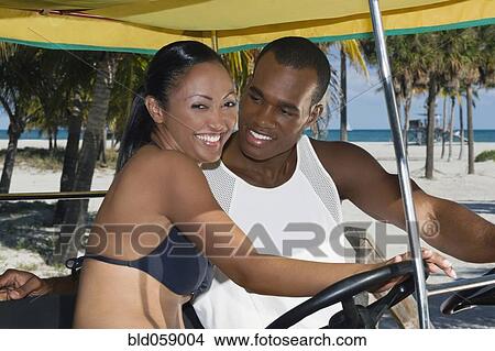 Picture - Multi-ethnic couple riding in pedal cart. Fotosearch