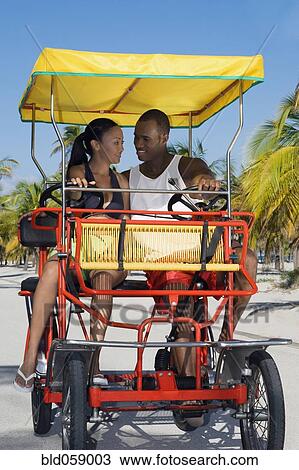 Stock Image - Multi-ethnic couple riding in pedal cart. Fotosearch