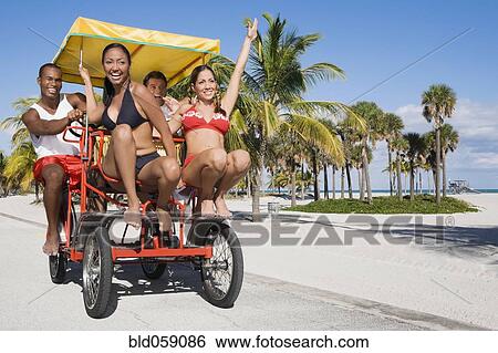 Stock Photograph - Multi-ethnic couples riding on pedal cart. Fotosearch